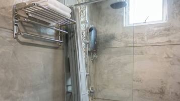 Un baño con ducha, inodoro y un perchero para toallas.