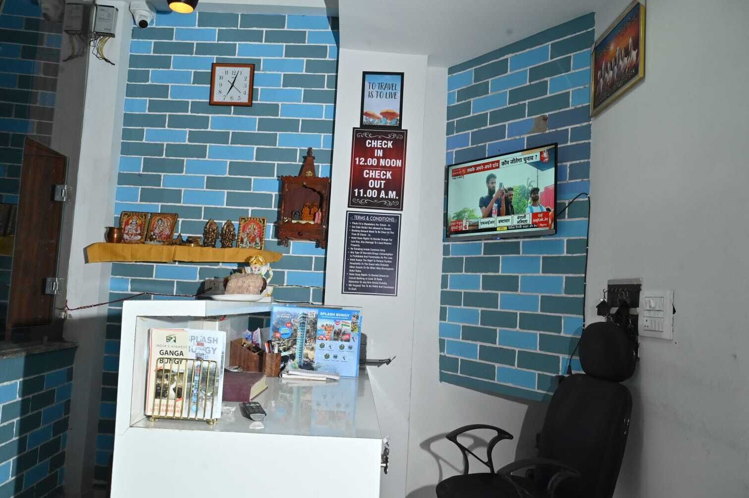 Zona de recepción con un reloj, una televisión y un cartel que indica horarios de registro de entrada y salida.