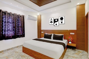 Un dormitorio moderno con una cama grande, un cabecero de madera, una mesita de noche con un florero y una obra de arte en la pared.