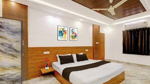 A modern bedroom with a wooden headboard, a large bed, a nightstand with a vase, and abstract art on the wall.