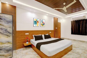 Um quarto moderno com cabeceira de madeira, uma cama grande, uma mesa de cabeceira com um vaso e arte abstrata na parede.