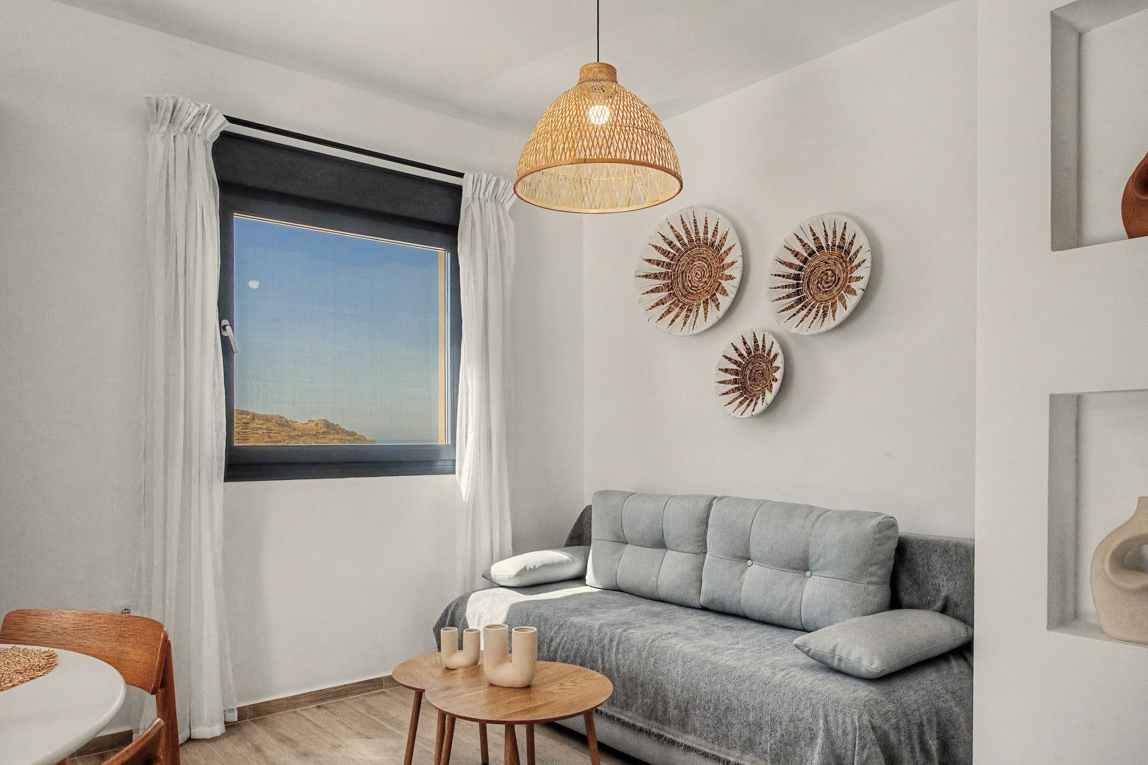 A modern living room with a grey sofa, a round wooden table with candles, and wall art.