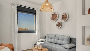A modern living room with a grey sofa, a round wooden table with candles, and wall art.