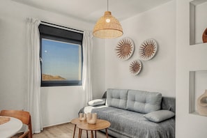 A modern living room with a grey sofa, a round wooden table with candles, and wall art.