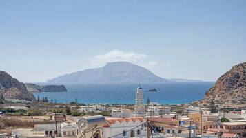 A coastal town with a prominent church tower, rocky cliffs, and a mountain in the background.