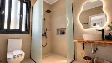 Ein modernes Badezimmer mit Toilette, einer Duschkabine aus Glas, einem Waschbecken mit Holzplatte und einem Spiegel mit außergewöhnlichem Lichtdesign.