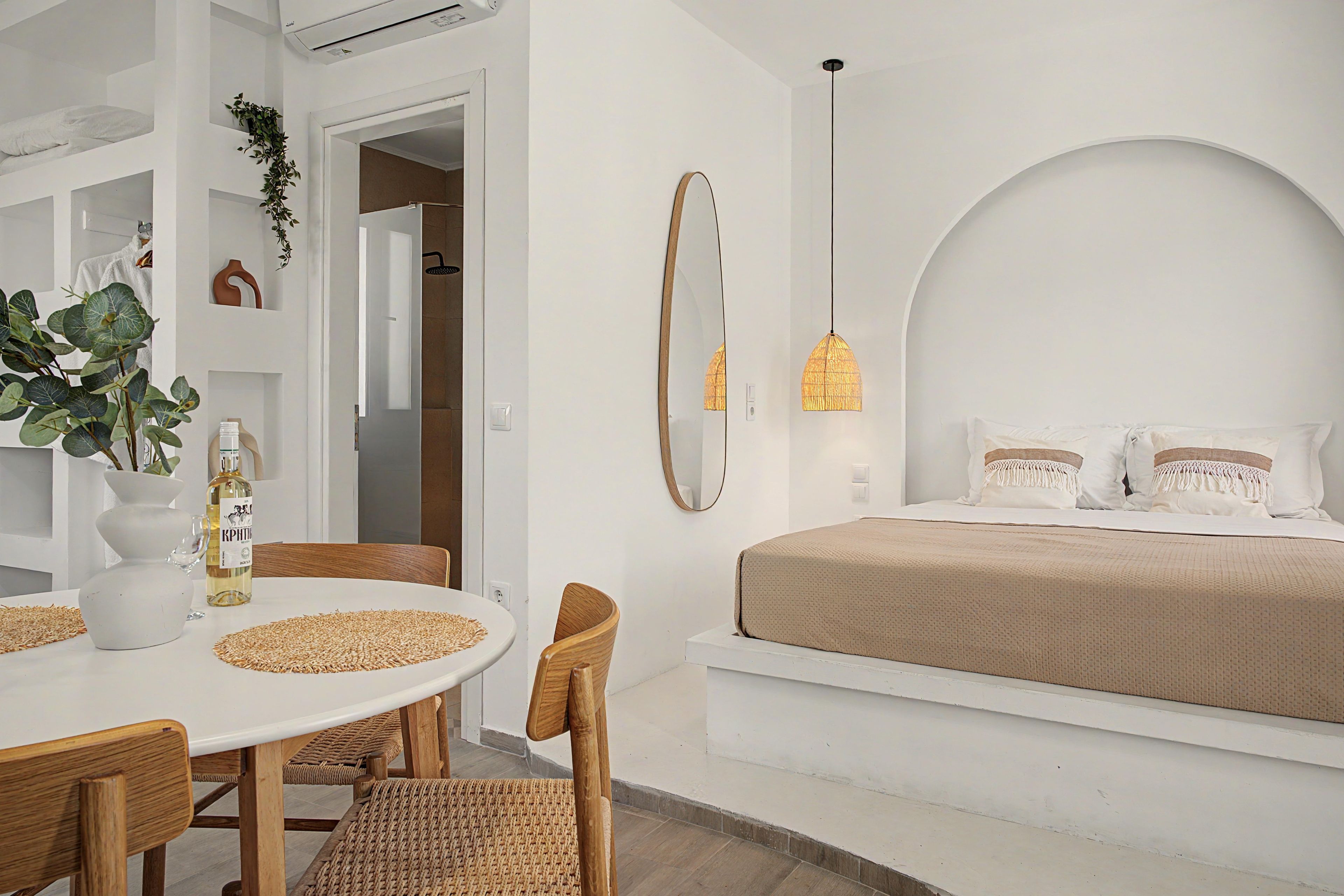 Ein modernes Schlafzimmer mit Bett, Nachttisch und einer Essecke mit Stühlen und Tisch.