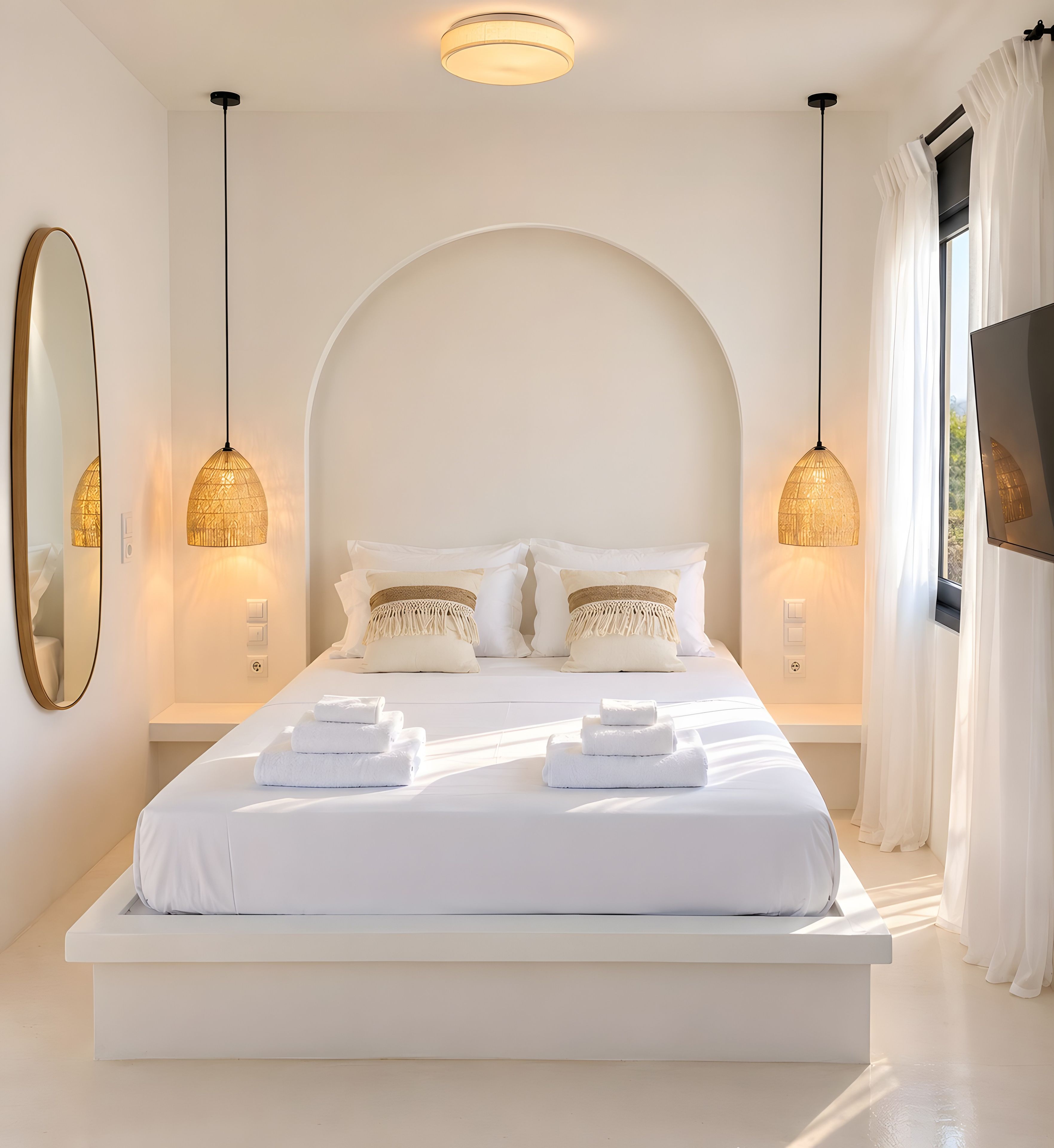 A modern bedroom with a large bed, two bedside lamps, and a large mirror.