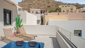 Une terrasse sur le toit avec une piscine, des chaises longues et une vue sur les bâtiments et les collines environnants.