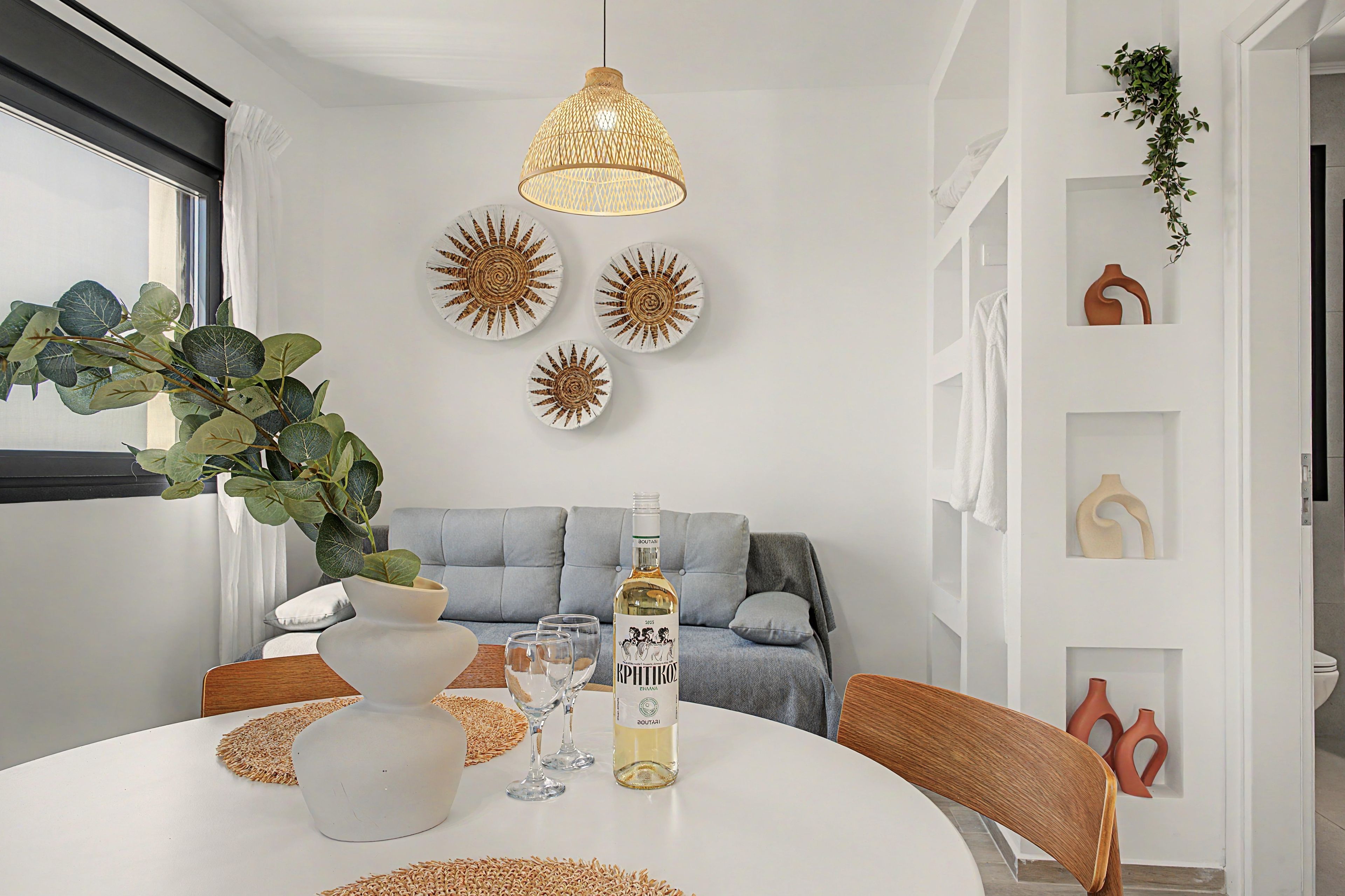 A dining area with a round table, a bottle of wine, and decorative plates.