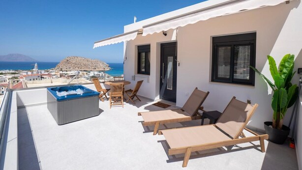 Une terrasse sur le toit avec un jacuzzi, des chaises longues et une vue sur la mer.
