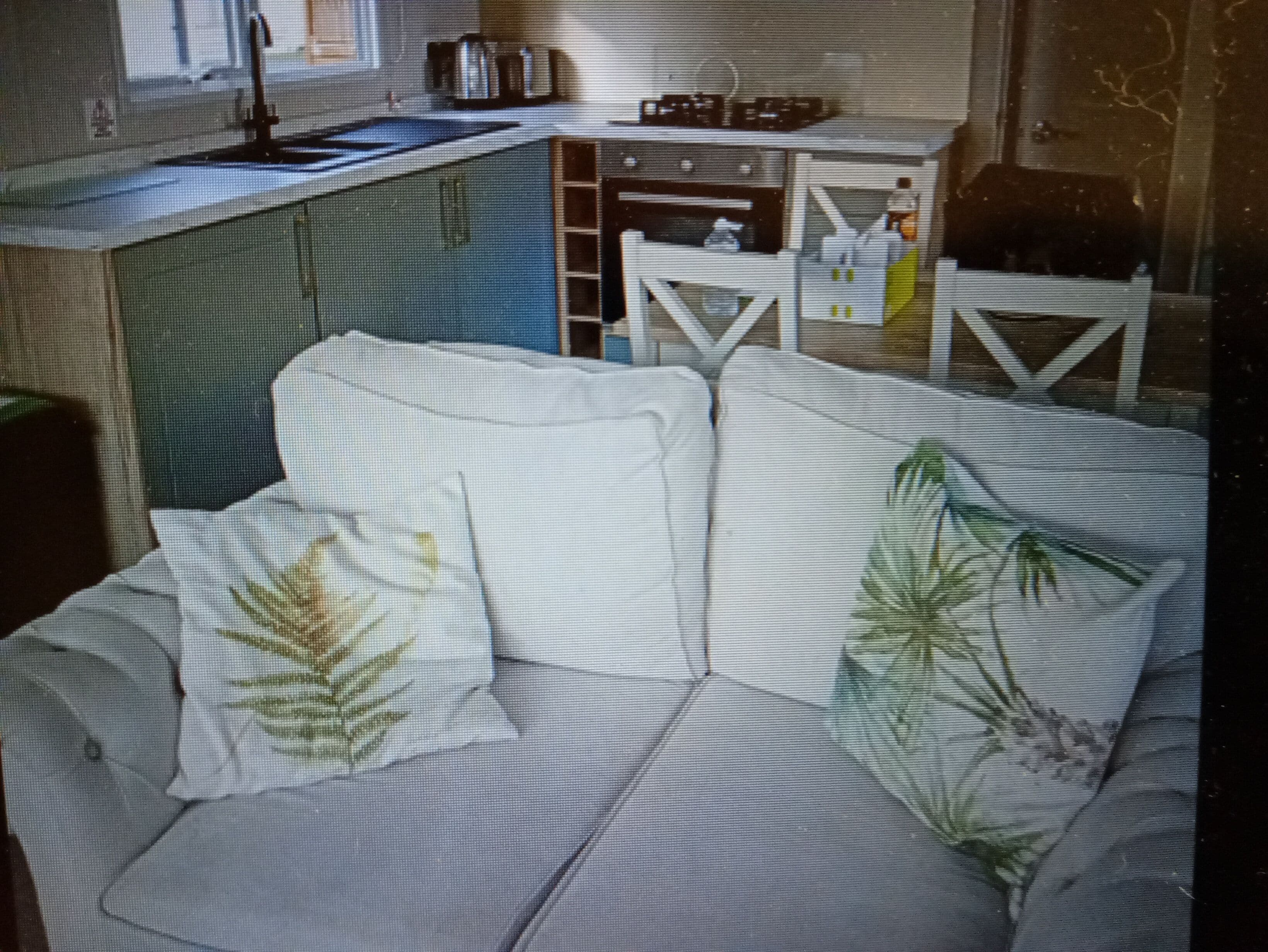 A living room with a sofa, a coffee table, and a kitchen area with a sink and cabinets.