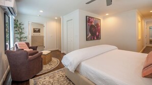 Um quarto com uma cama, uma cadeira, um ventilador de teto e um quadro na parede.