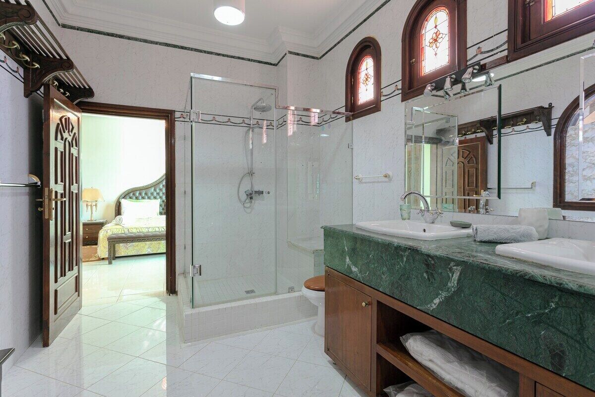 Un bagno con doccia vetrata, lavabo in marmo e mobile contenitore in legno.