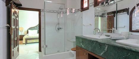 Un bagno con doccia vetrata, lavabo in marmo e mobile contenitore in legno.