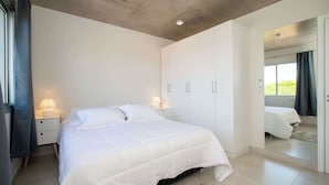 A bedroom with a bed, nightstands, a wardrobe, and a mirror.