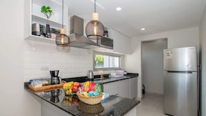 A modern kitchen with a central island, stainless steel appliances, and pendant lighting.