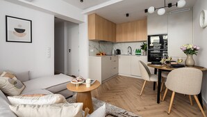 Une cuisine moderne avec des meubles en bois, un coin repas avec une table et des chaises, et un salon avec un canapé et des coussins.