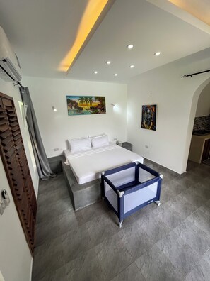 Une chambre à coucher moderne avec un lit, une petite table de chevet, une commode, un tableau au mur et un luminaire rouge fixé au mur.