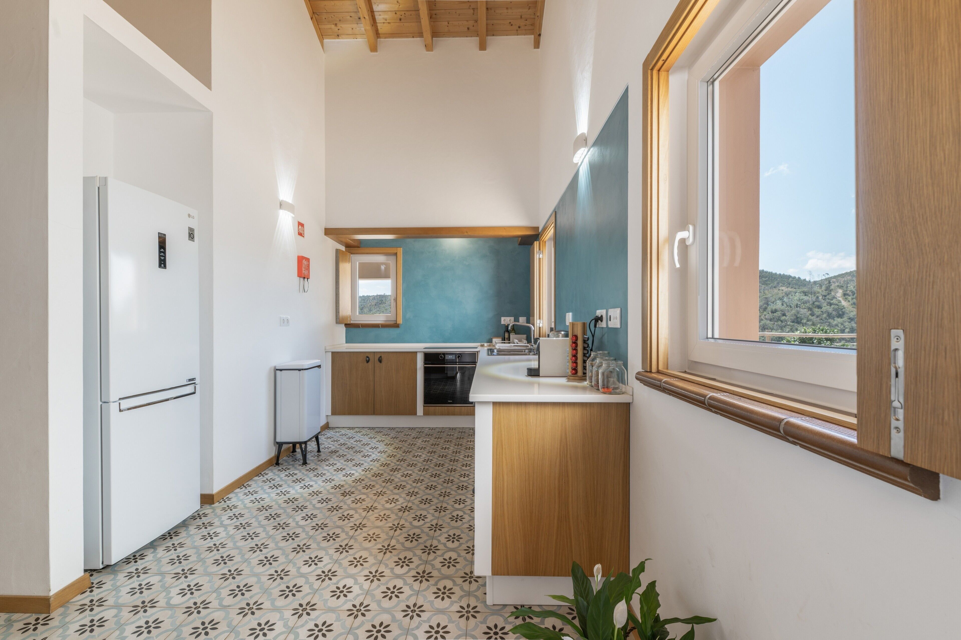 A compact kitchen with a refrigerator, oven, and a window with a view of the outdoors.
