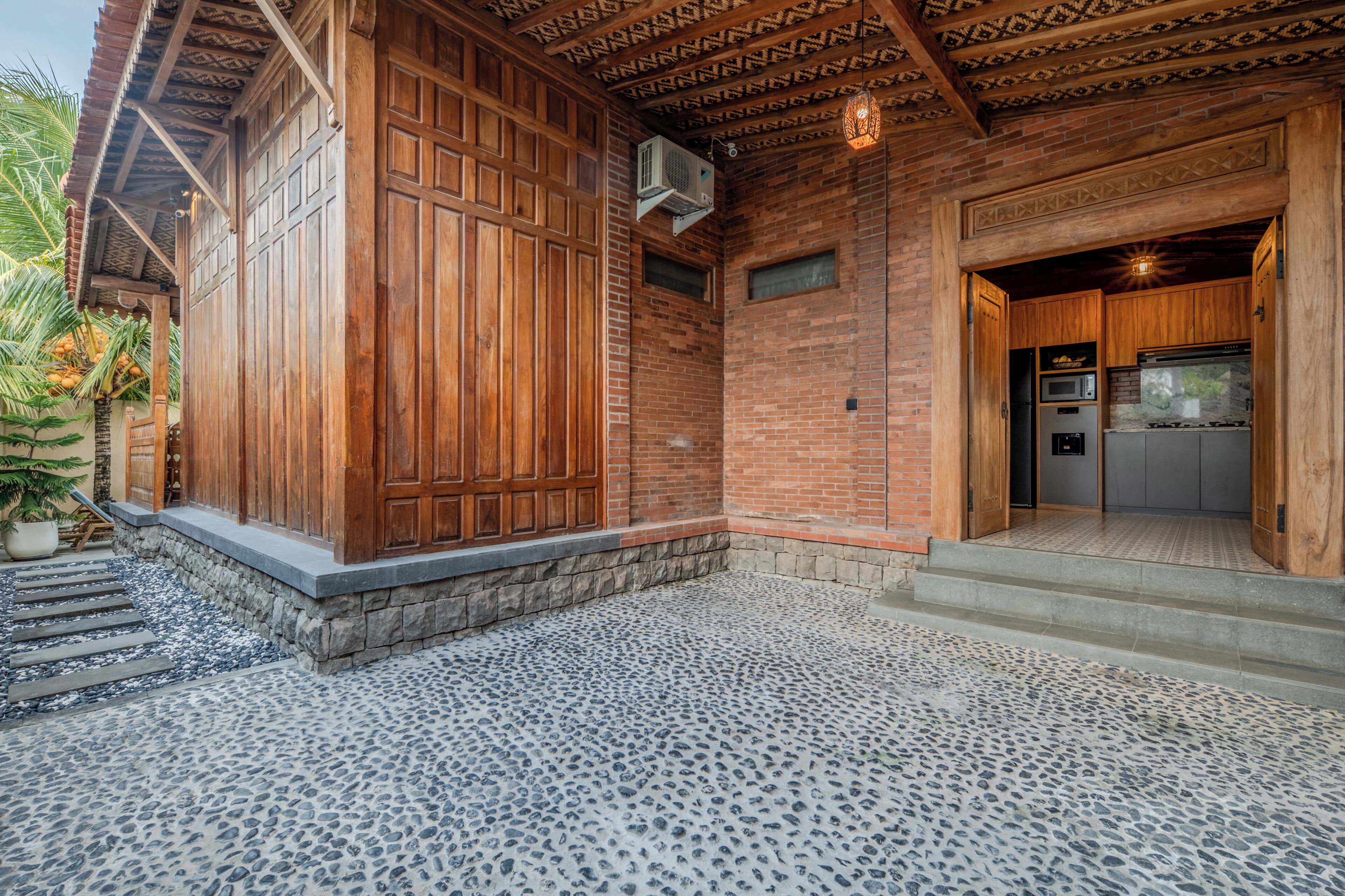 A building with a wooden exterior, a stone-paved entrance, and a brick wall.