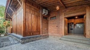 A building with a wooden exterior, a stone-paved entrance, and a brick wall. - Omah Nyang Uluwatu (Uluwatu)