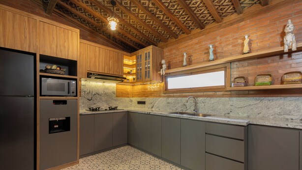 A kitchen with wooden cabinets, a microwave, a sink, and decorative items on shelves. - Omah Nyang Uluwatu (Uluwatu)