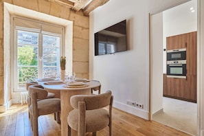 Un espace repas comprenant une table ronde, des chaises et un téléviseur fixé au mur.