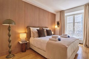 Une chambre d’hôtel avec un grand lit, une lampe, une table de chevet et une vue sur l’extérieur.