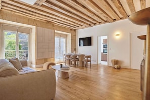 Un vaste espace de vie doté d’un plafond en bois, d’une table à manger et d’un canapé.