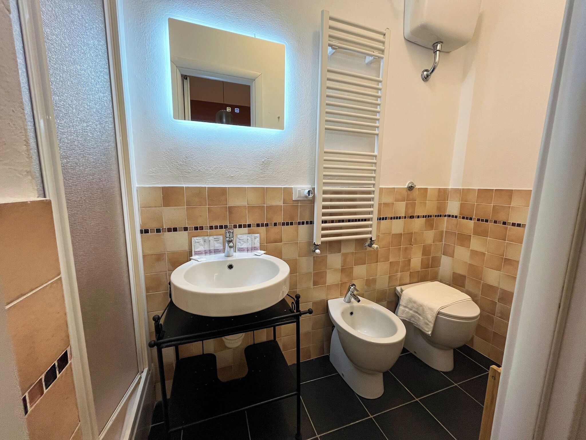 Un baño con lavamanos, bidé, inodoro y espejo.