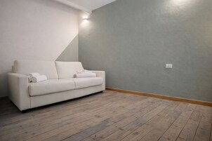 Una habitación con un sofá blanco, suelo de madera y pared gris.