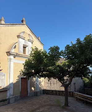 A building with a stone wall, a wooden door, and a tree in front. - Village House (Silvareccio)