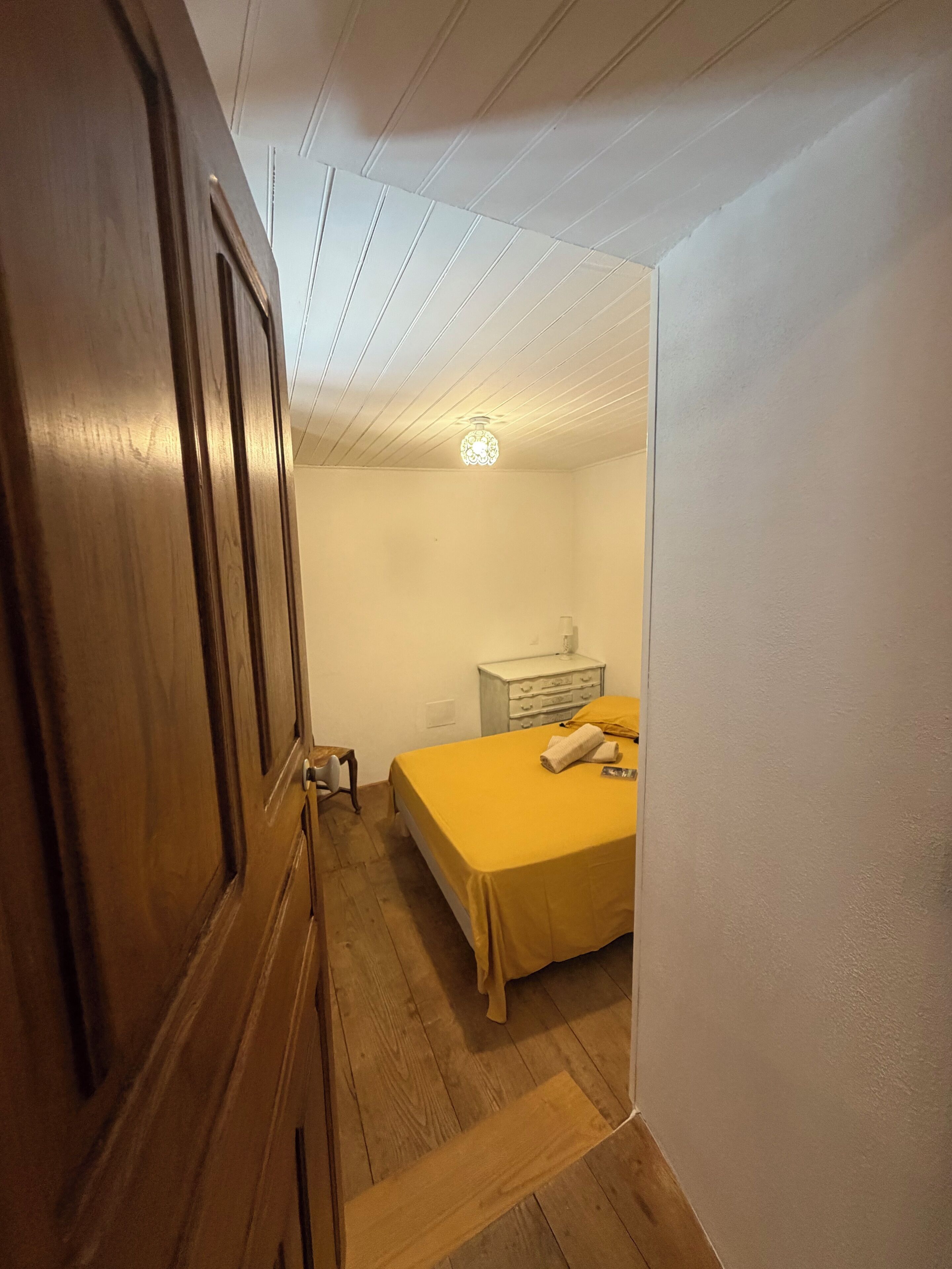 Un dormitorio con cama, mesita de noche, cómoda y lámpara en el techo.