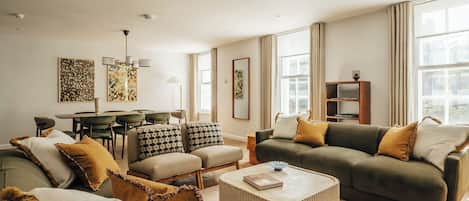 Uma sala de estar moderna com um sofá, uma mesa de centro e uma área de jantar com cadeiras e uma mesa.