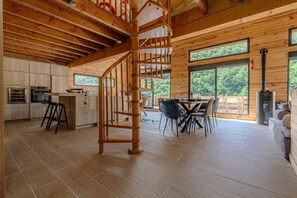 A wooden interior with a spiral staircase, a dining area with chairs, and a kitchen with cabinets and appliances.