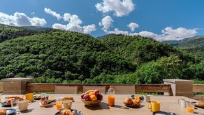 A table set with breakfast items and a view of a forested mountain. - L'Écrin Secret Chalet•Swimming Pool•Mountain View•12pers (Fontpédrouse)