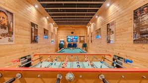A room with wooden walls, a foosball table, a pool table, and a television screen. - L'Écrin Secret Chalet•Swimming Pool•Mountain View•12pers (Fontpédrouse)