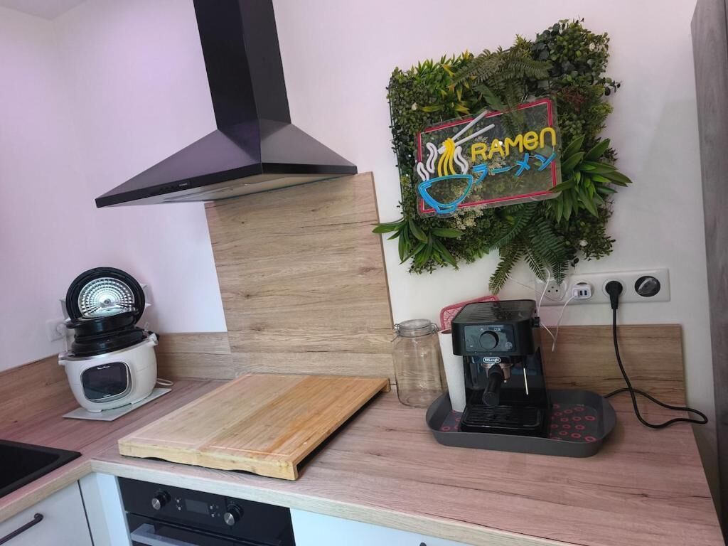 Une cuisine équipée d’une cuisinière, d’une machine à café, d’une planche à découper et d’un panneau fixé au mur.