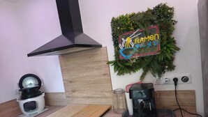 Una cocina con estufa, cafetera, tabla de cortar y un letrero en la pared.