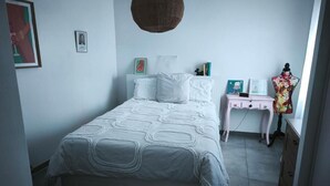 Un dormitorio con cama, mesita de noche, cómoda y lámpara colgante.