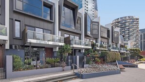 Een modern gebouw met grote ramen, een balkon en een unieke, gebogen constructie op de achtergrond.
