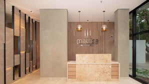 Mostrador de recepción con un fondo de madera, dos lámparas colgantes y una encimera de mármol.