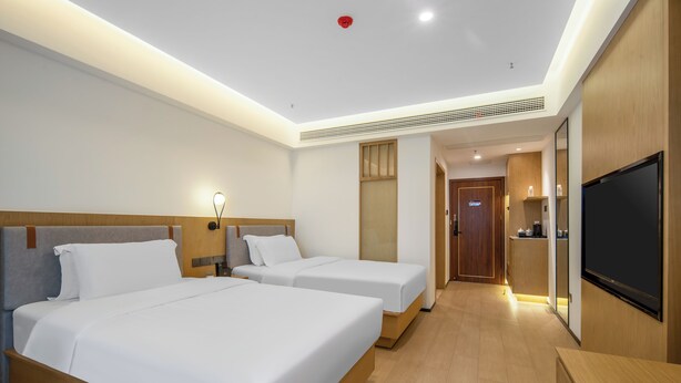 A hotel room with two beds, a TV, a desk, and a bathroom door. - Zhangjiajie New Pipaxi Courtyard Hotel (Zhangjiajie)