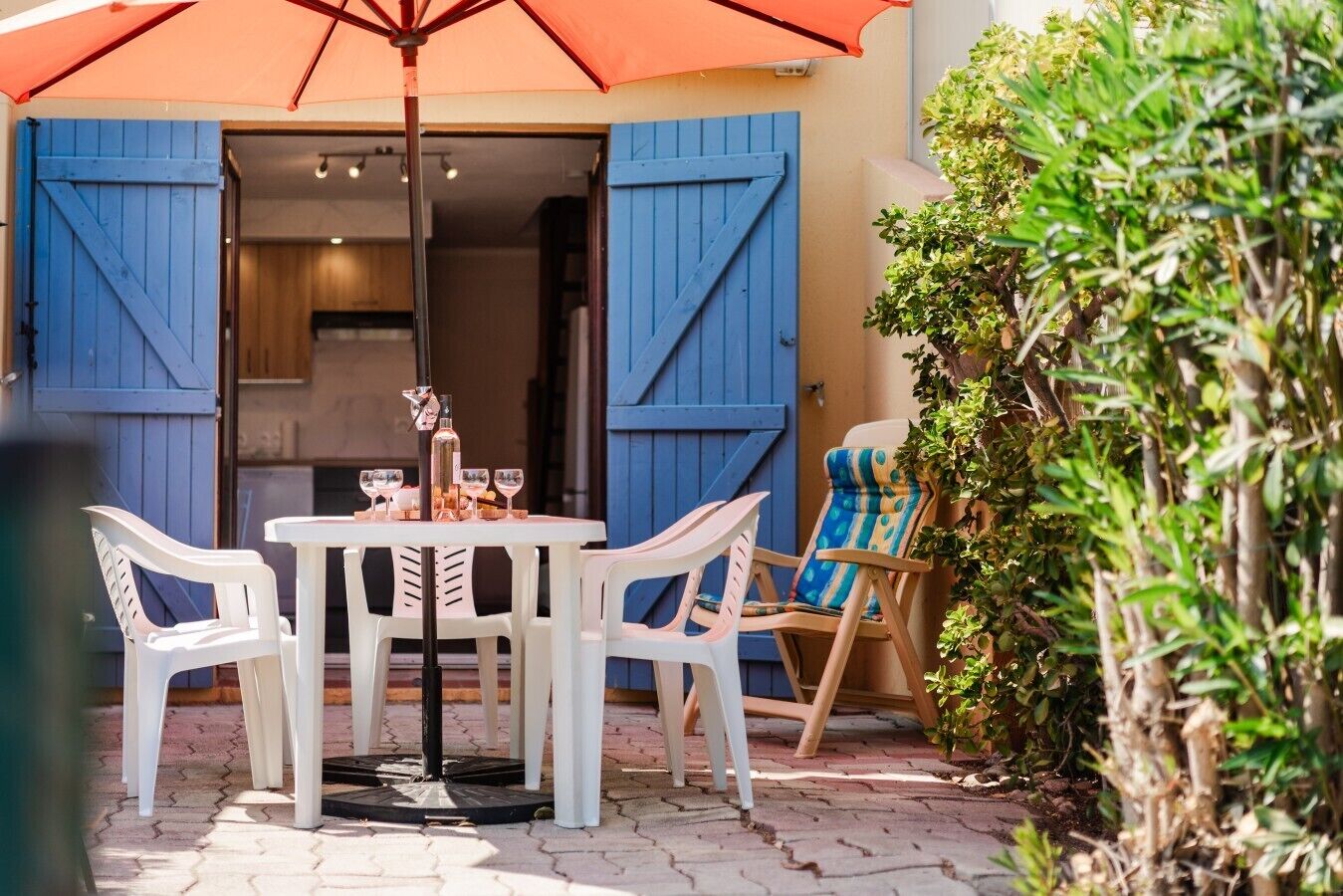 Un espace extérieur aménagé avec une table et des chaises, une bouteille d’eau et des verres.