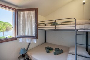 A bunk bed room with a window, a lamp, and a view of greenery. - House for 5 people • Swimming Pool • Beach within walking distance • Air Conditioning (Le Barcarès)