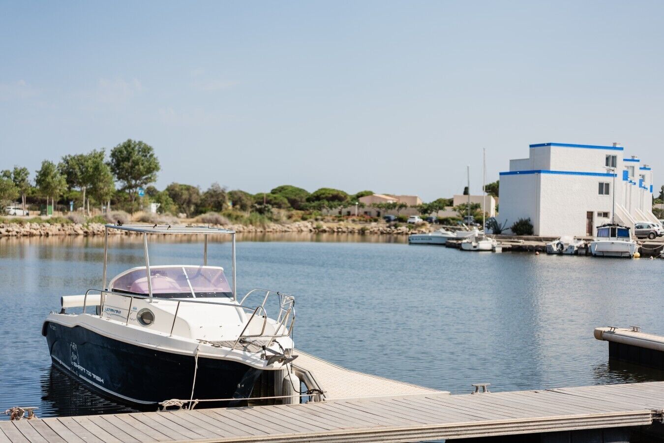 Un port de plaisance avec des bateaux amarrés, une jetée en bois et un bâtiment avec un toit bleu.