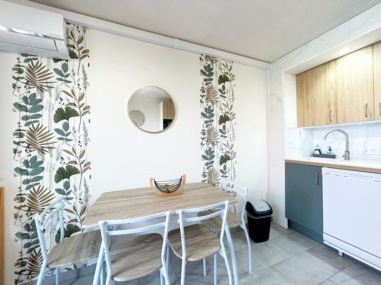Una cocina compacta con una mesa de comedor, sillas, un espejo y un lavabo.