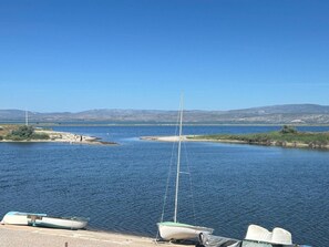 A calm lake with boats docked, a clear sky, and distant mountains.