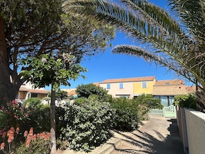 A residential area with houses, a pathway, and lush greenery. - House for 5 people • Swimming Pool • Beach within walking distance • Air Conditioning (Le Barcarès)